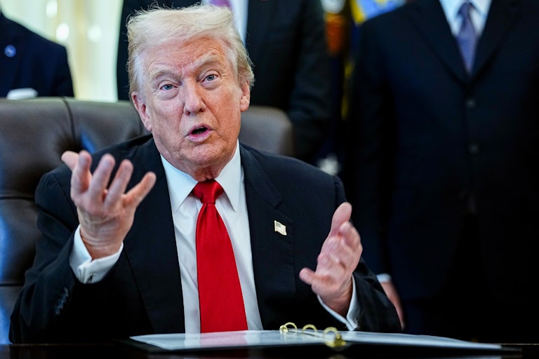 Donald Trump speaks with both hands while sitting behind his desk in the Oval Office of the White House. (He seems like he's pleading, or confused.)