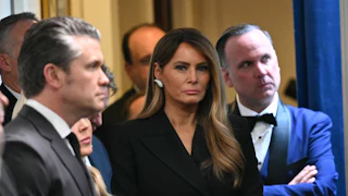 First Lady Melania Trump stands near a group of people including Defense Secretary Pete Hegseth