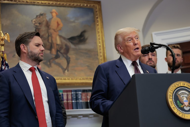 JD Vance watches while Donald Trump speaks at a podium