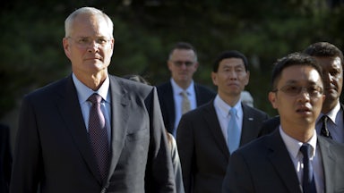 Exxon Mobil CEO Darren Woods walks with several other people.