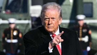 Donald Trump points while walking to Air Force One at Joint Base Andrews in Maryland. The wind blows his hair back.