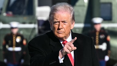 Donald Trump points while walking to Air Force One at Joint Base Andrews in Maryland. The wind blows his hair back.