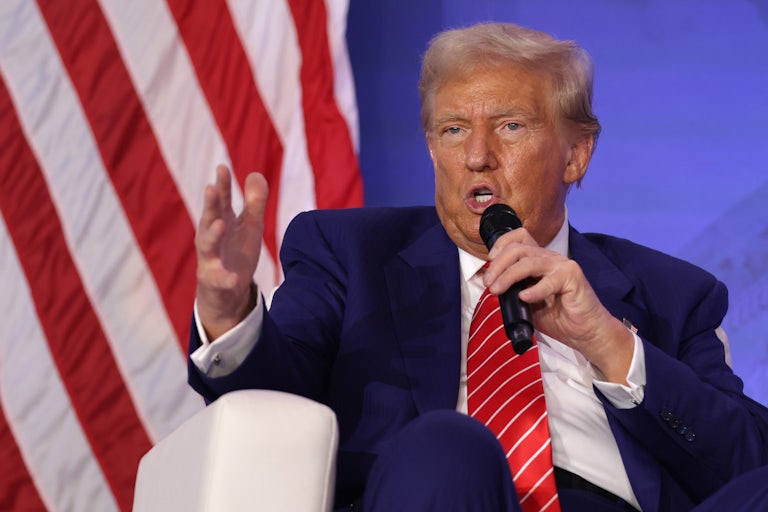Donald Trump speaking as he holds a mic to his mouth