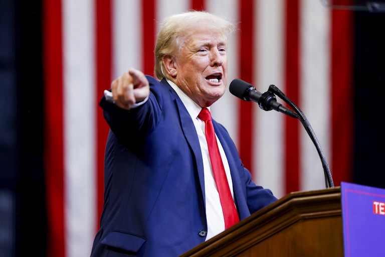 Donald Trump speaks at a podium and points a finger