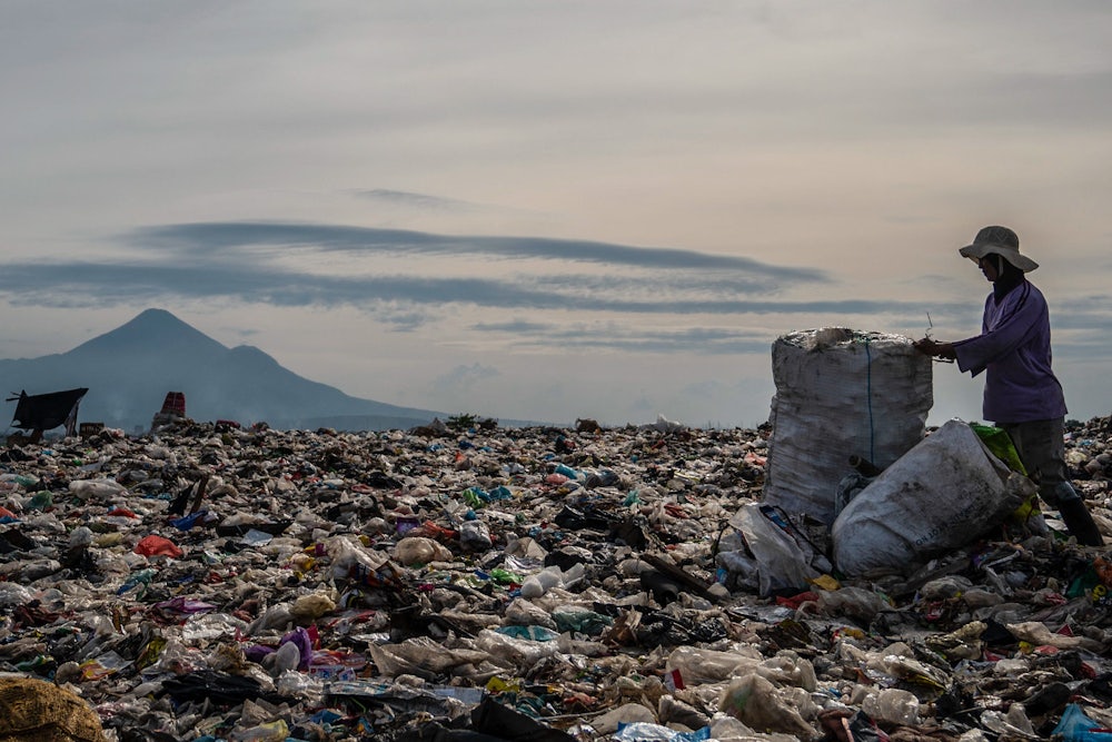 A ragpicker collects recyclable materials at a landfill in Sidoarjo, Indonesia, 2022