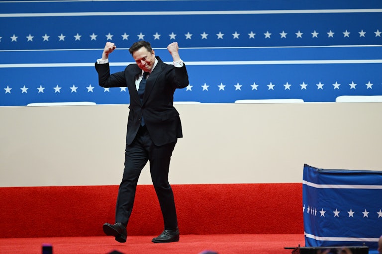 Elon Musk pumps his fists while walking on stage during Donald Trump’s inauguration parade