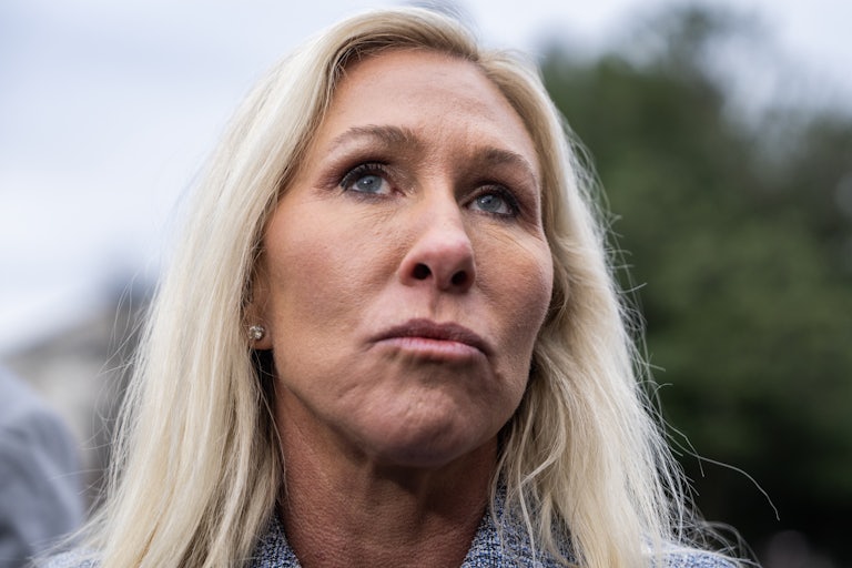 Marjorie Taylor Greene looks up while speaking to reporters