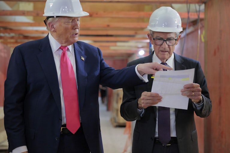 Donald Trump and Jerome Powell wear hard hats at the Federal Reserve. Powell looks at a piece of paper in his hands in confusion, while Trump points to something on the paper.