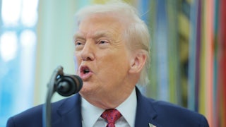 Donald Trump speaks into a microphone in the Oval Office