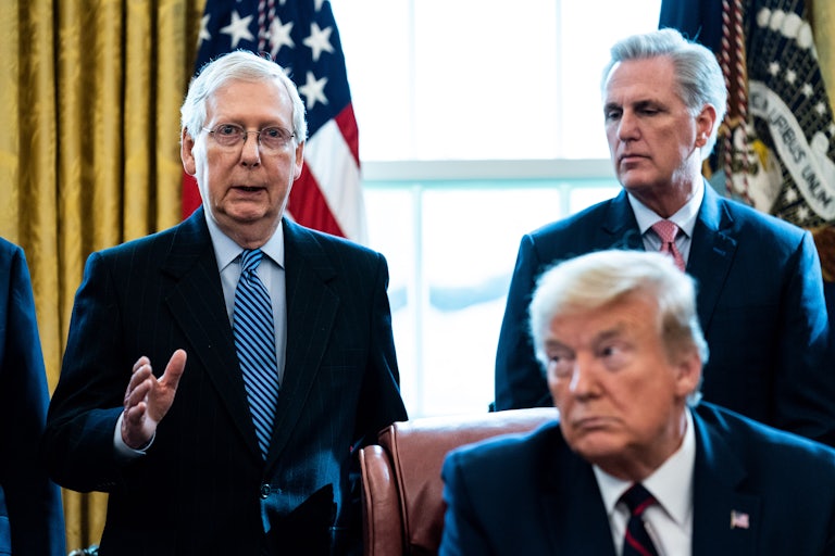 Mitch McConnell and Kevin McCarthy stand in the background, Trump sits in the foreground (not in focus)