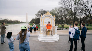 Someone sits on the golden toilet throne near the Reflecting Pool.