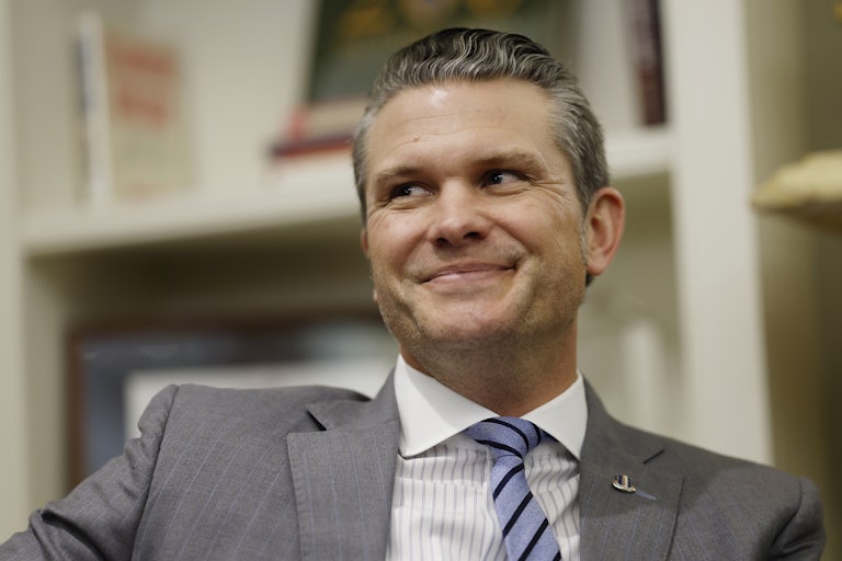 Pete Hegseth leans back and smiles.
