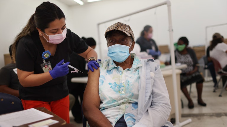 A nurse administers a Moderna COVID-19 vaccine to a masked patient at a clinic in Florida.
