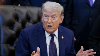 President Donald Trump speaks angrily while making hand gestures and sitting at his desk in the Oval Office of the White House.