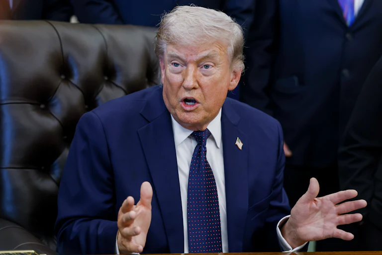 President Donald Trump speaks angrily while making hand gestures and sitting at his desk in the Oval Office of the White House.