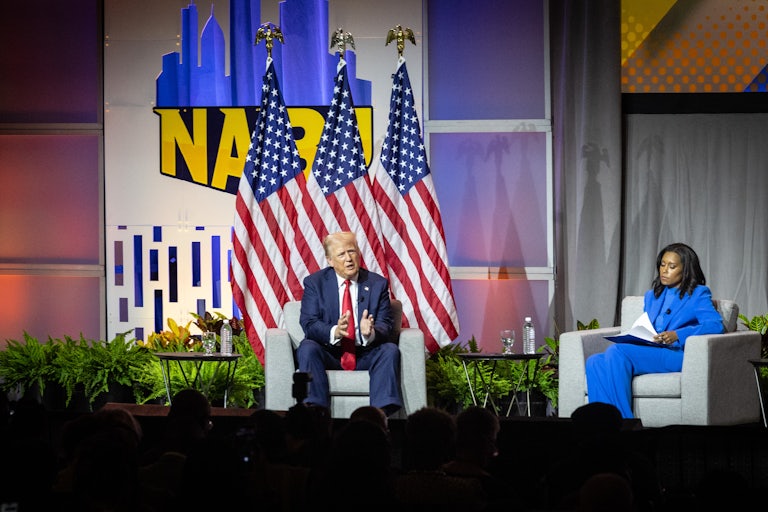 Donald Trump speaks while sitting onstage next ABC News reporter Rachel Scott at the National Association of Black Journalists