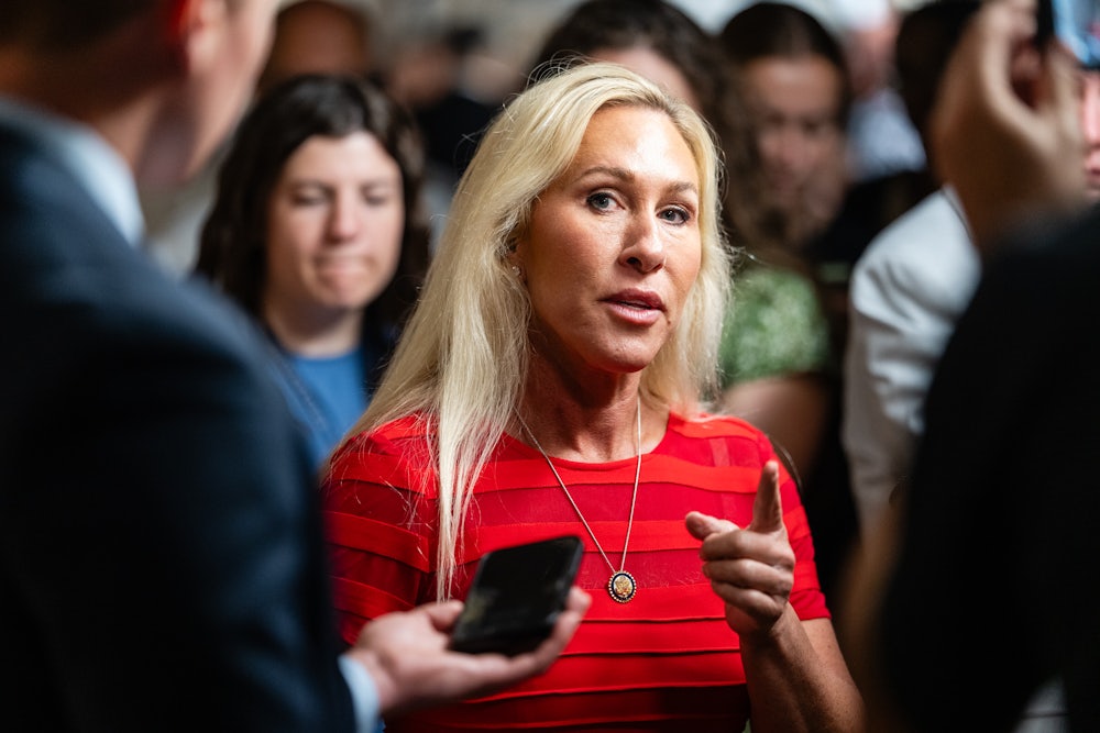 Representative Marjorie Taylor Greene points while speaking to reporters in the Capitol.