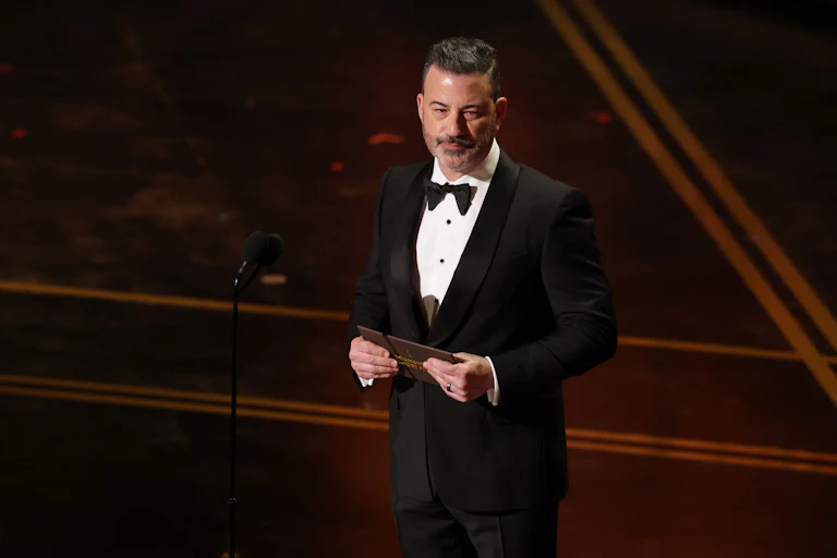 Jimmy Kimmel holds a notecard in his hands as he stands on the Oscars stage.