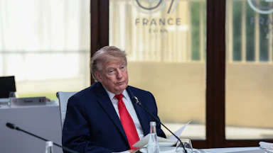 Donald Trump sits at a table during the G7 summit