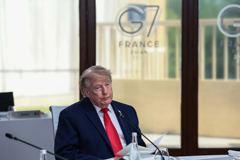Donald Trump sits at a table during the G7 summit