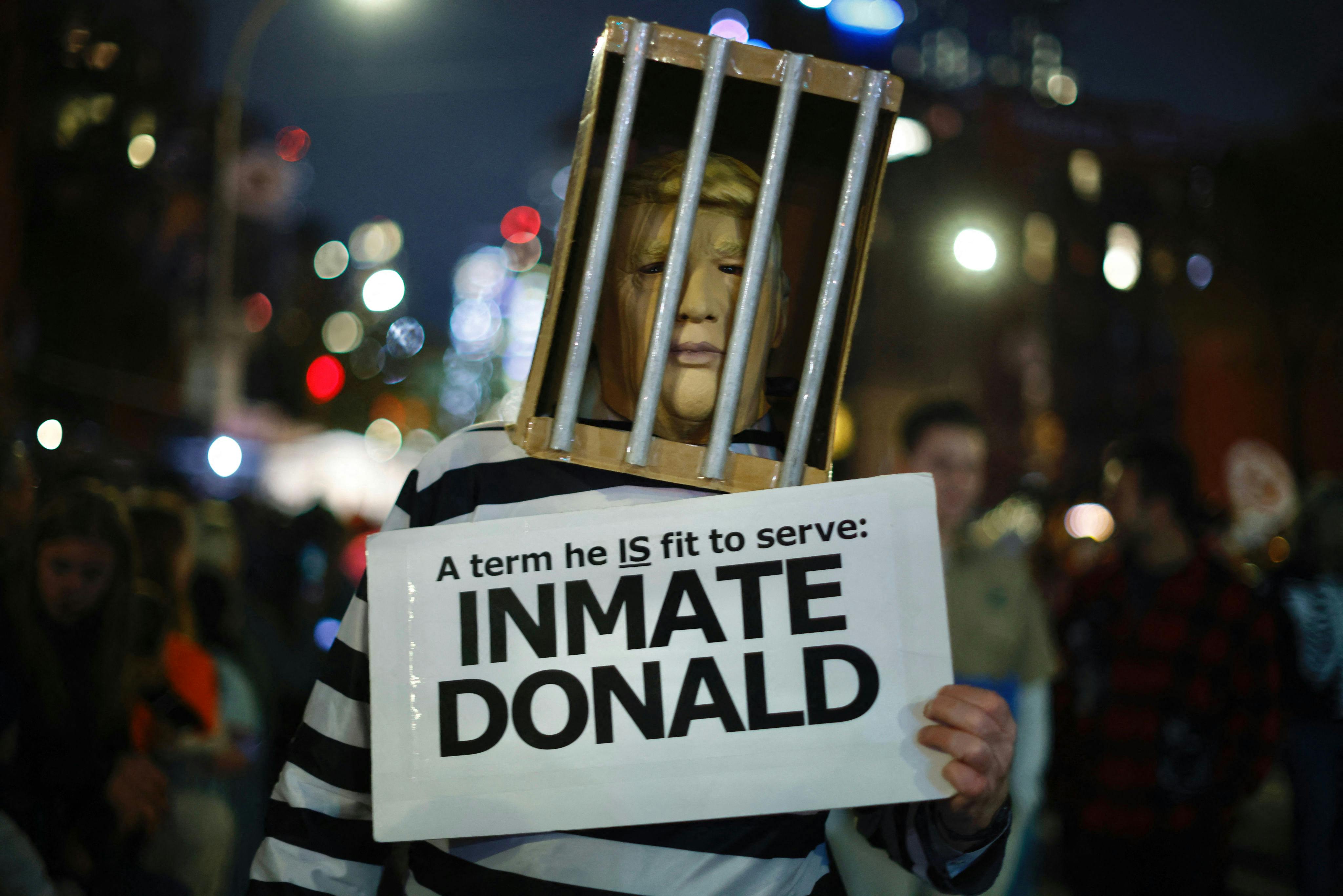 A man dressed as former US President Donald Trump behind bars holding an "Inmate Donald" sign, walks during the Annual Village Halloween parade in New York City.