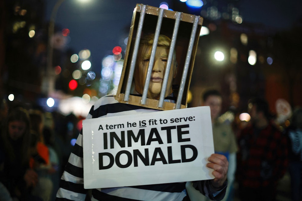 A man dressed as former US President Donald Trump behind bars holding an "Inmate Donald" sign, walks during the Annual Village Halloween parade in New York City.