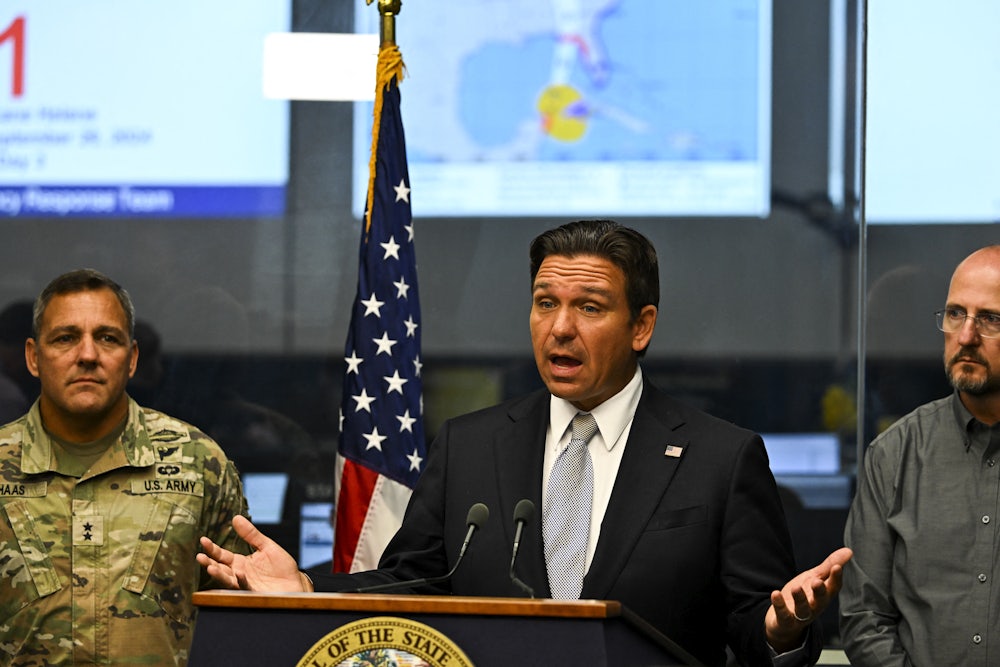 DeSantis speaks at a lectern surrounded by two others.