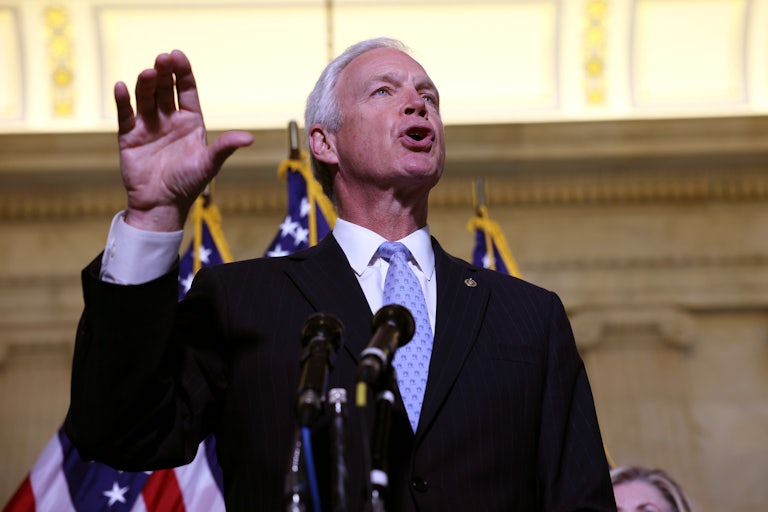 Senator Ron Johnson raises his hand while addressing reporters at a press conference on Capitol Hill