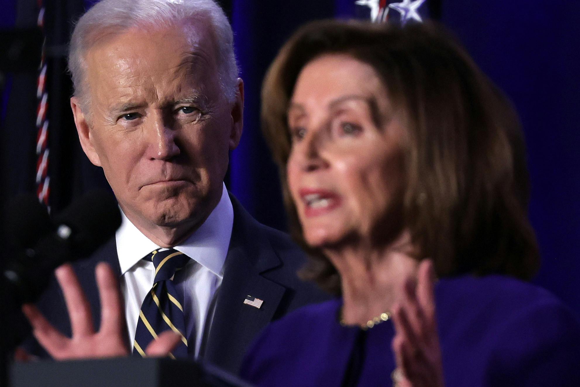 President Joe Biden stands back, watching Nancy Pelosi speak.