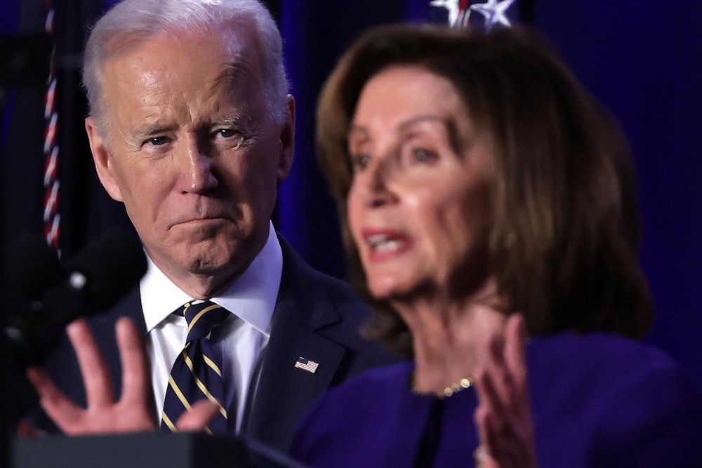President Joe Biden stands back, watching Nancy Pelosi speak.