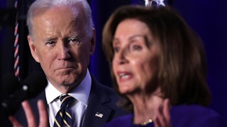 President Joe Biden stands back, watching Nancy Pelosi speak.