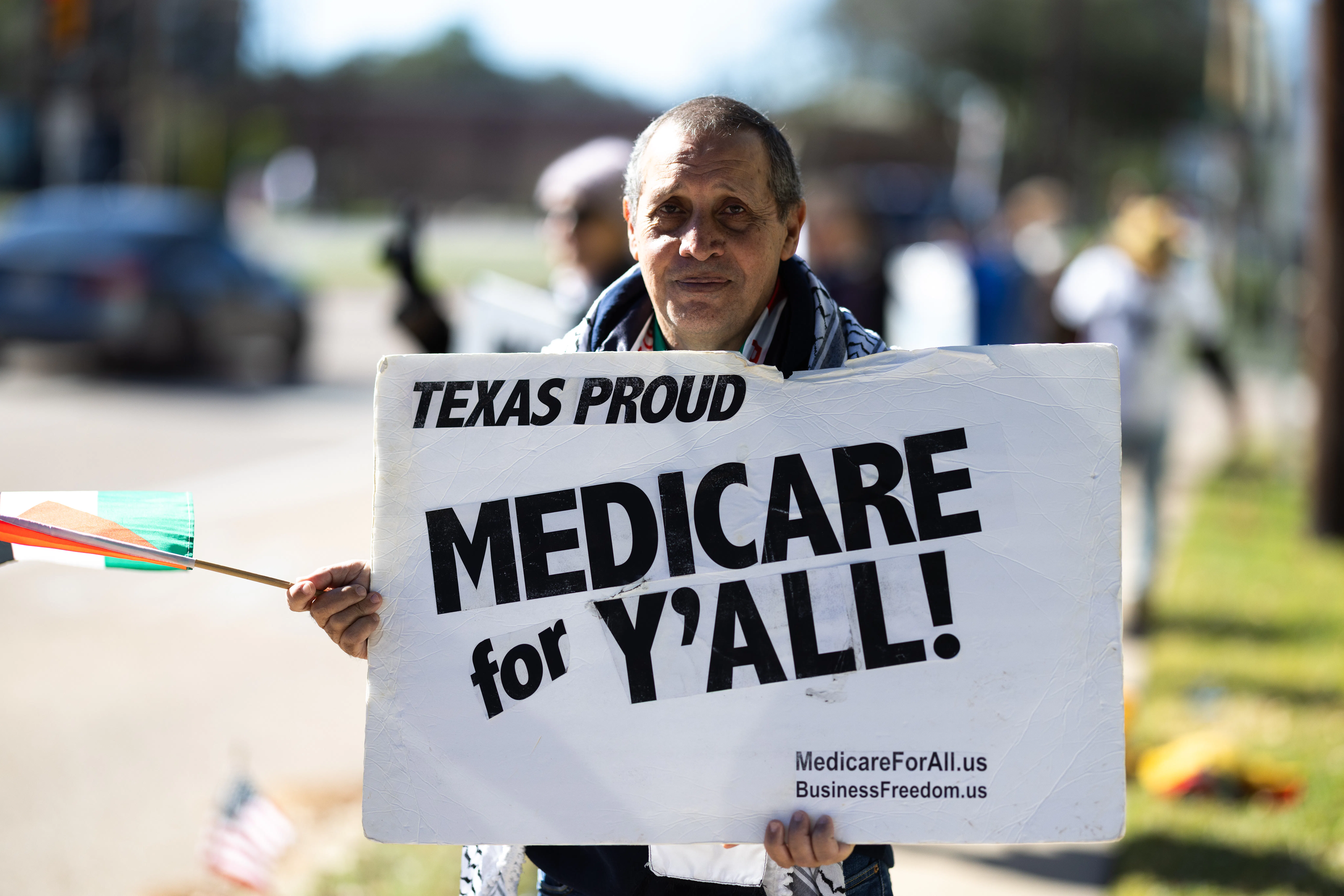 A protester holds a sign that reads, ''Texas Proud: Medicare for y'all'' 