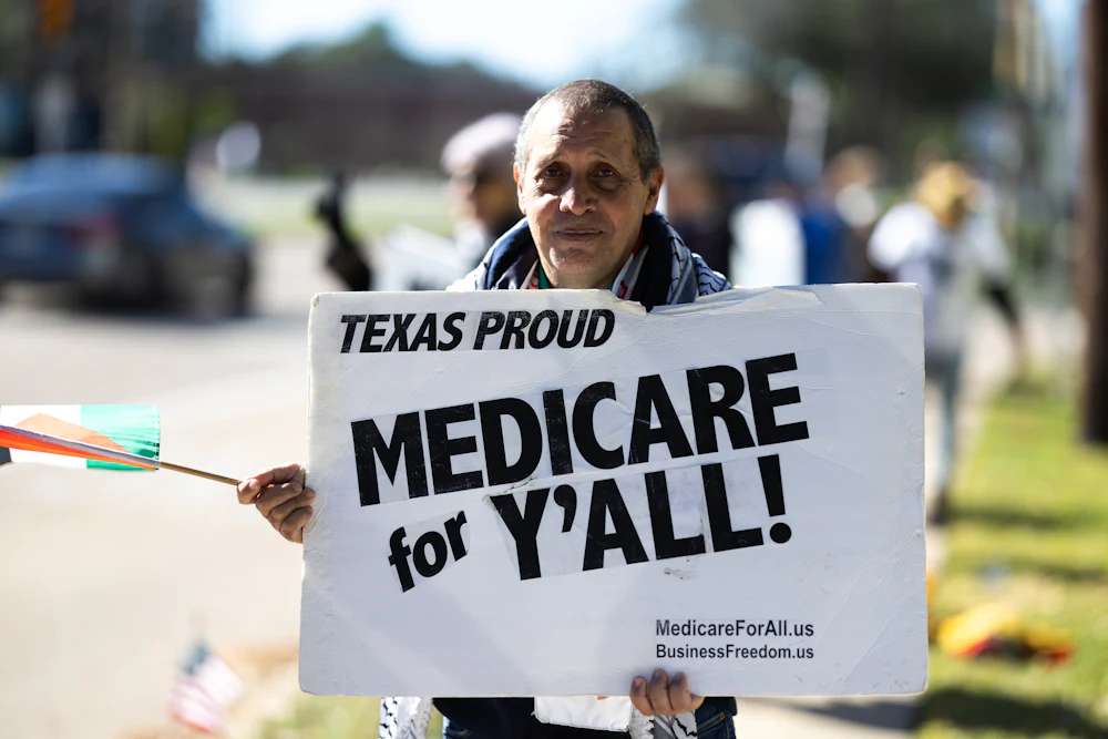 A protester holds a sign that reads, ''Texas Proud: Medicare for y'all''