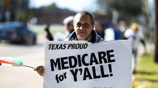 A protester holds a sign that reads, ''Texas Proud: Medicare for y'all''