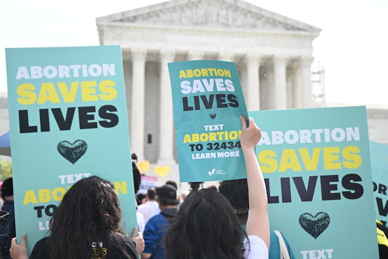 People hold up pro-abortion protest signs outside the Supreme Court