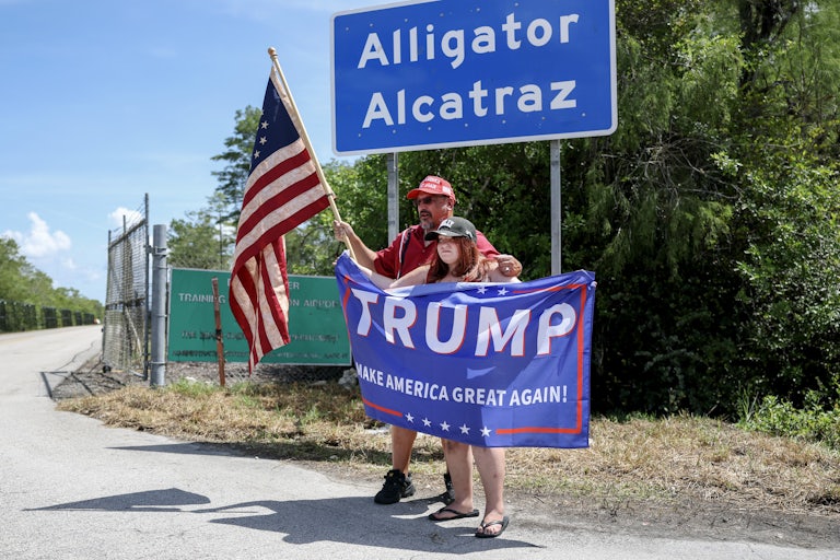 Trump supporters take photos in front of the sign for Alligator Alcatraz
