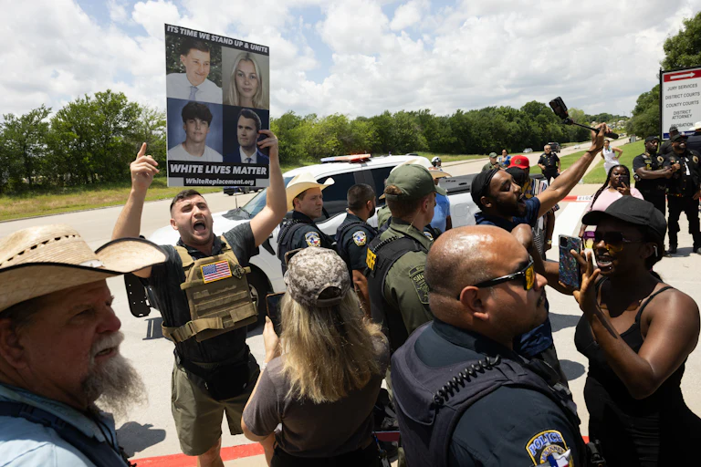 Pardoned January 6 rioter Jake Lang holds a sign that reads White Lives Matter while in a crowd outside the Collin County Courthouse.