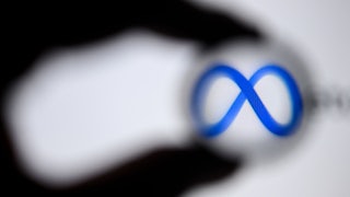 The shadow of a hand appears to encircle to logo for "Meta," the new name of Facebook's parent company.