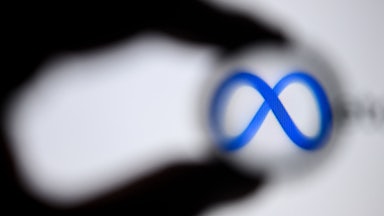 The shadow of a hand appears to encircle to logo for "Meta," the new name of Facebook's parent company.