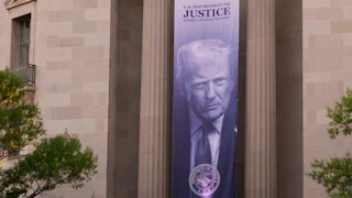 A banner of Donald Trump's face hangs from the Department of Justice building