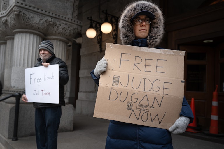 People hold up signs supporting Judge Hannah Dugan at a protest outside the Milwaukee County Courthouse