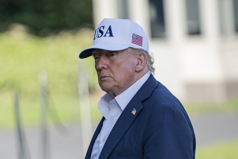 Donald Trump wears a white MAGA cap while outside.