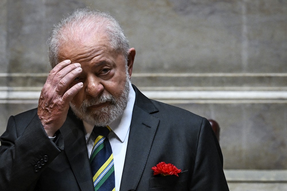 Luis Inacio Lula da Silva lifts his hand to his forehead.
