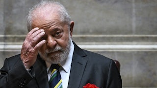 Luis Inacio Lula da Silva lifts his hand to his forehead.