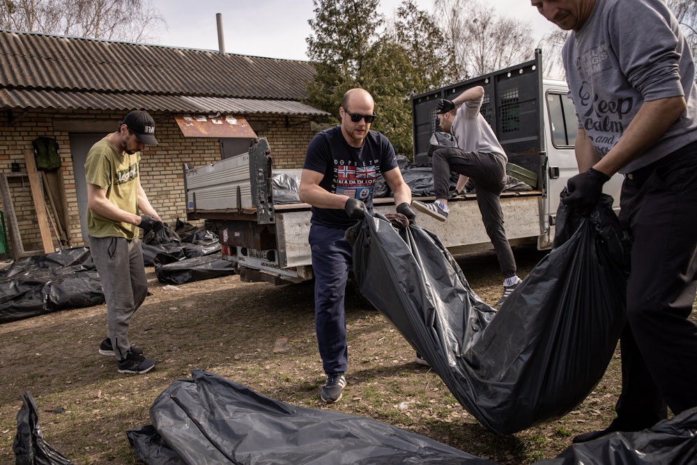 Two workers carry a body bag, with more in the background.