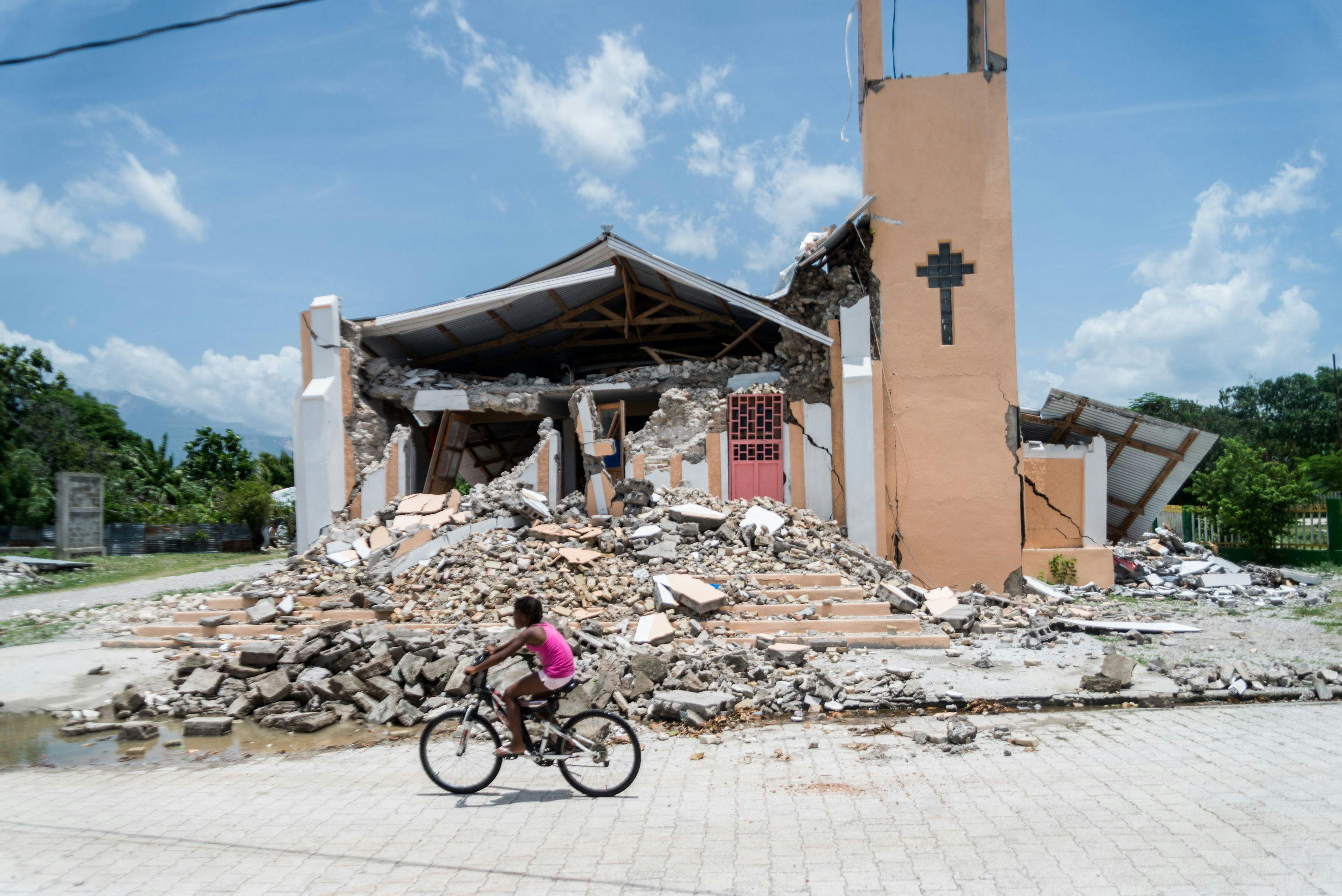 A child rides a bicycle in front of a church demolished by an earthquake in Chardonnières, Haiti.