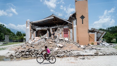 A child rides a bicycle in front of a church demolished by an earthquake in Chardonnières, Haiti.