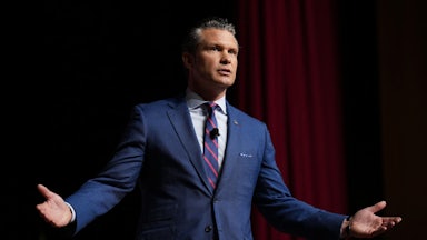 Pete Hegseth splays his arms out whiel speaking