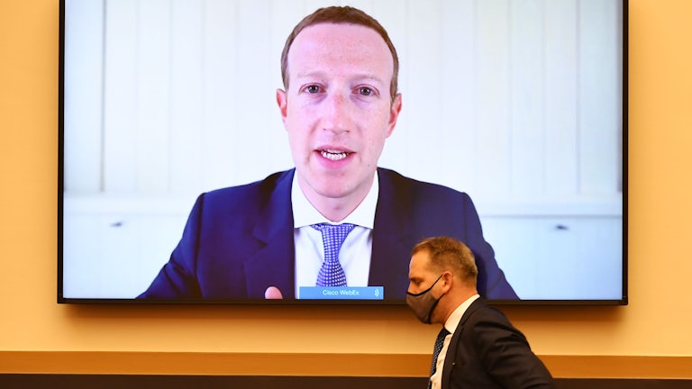 Mark Zuckerberg's face is broadcast on a large flatscreen TV as he testifies before Congress during an anti-trust hearing  
