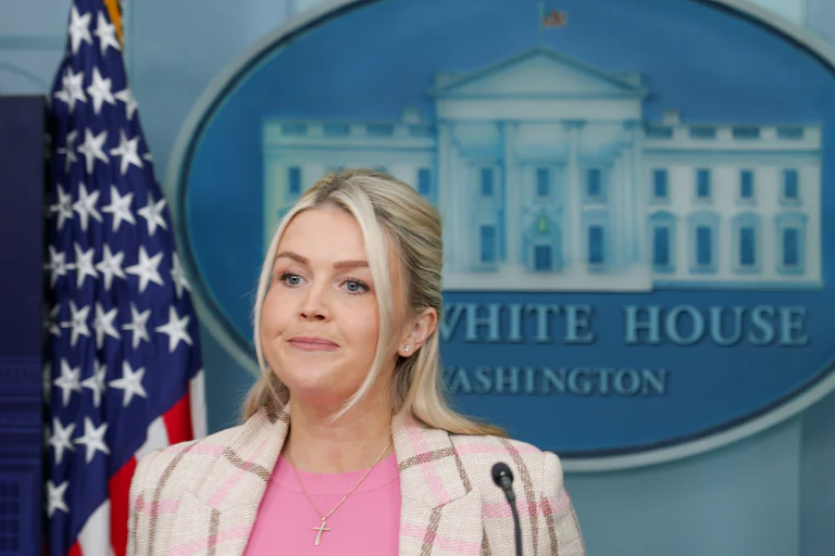White House press secretary Karoline Leavitt presses her lips together while standing during a press briefing